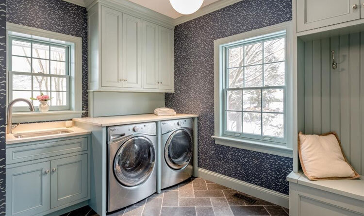 Laundry room with light green cabinets and wallpaper